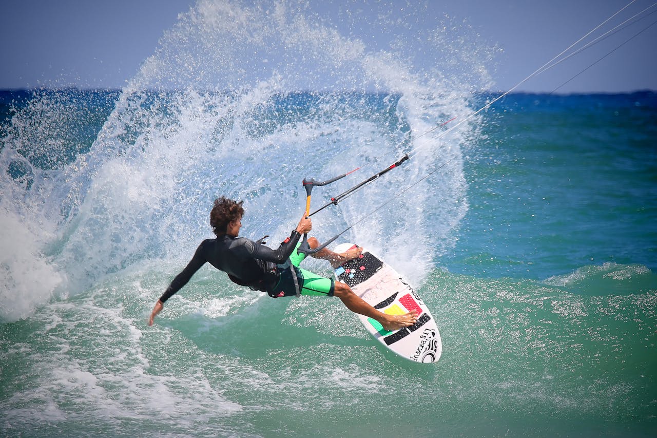A kiteboarder performing thrilling maneuvers on ocean waves on a sunny day.